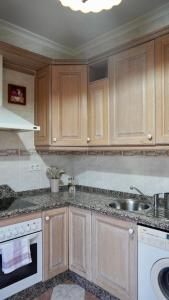 a kitchen with wooden cabinets and a sink at Al ladito de Sevilla in Bormujos
