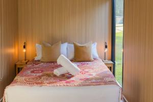 a bedroom with a bed with pillows and a window at Dreamseed Cabin by Tiny Away in Yandina