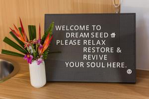a sign on a counter with a vase of flowers at Dreamseed Cabin by Tiny Away in Yandina