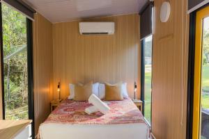a bedroom with a bed and a large window at Dreamseed Cabin by Tiny Away in Yandina