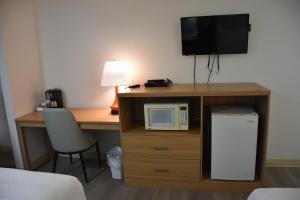 a room with a desk with a microwave and a television at Howard Johnson by Wyndham Hinton in Hinton