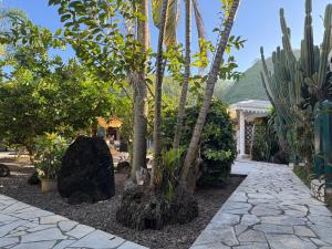 a garden with palm trees and a stone walkway at Relais Fenua in Punaauia +18 photos