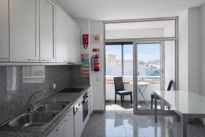 a kitchen with a sink and a table with a chair at Free Wave Rooms in Maia