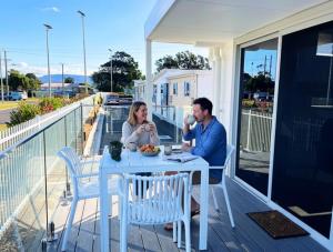 a man and woman sitting at a table on a balcony at Resort on Cedar in Windang