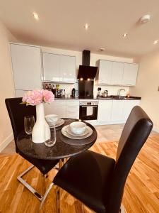 a kitchen with a table with a vase of flowers on it at Cardiff City Center - FREE On-Site Parking in Cardiff +12 photos
