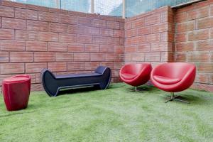 two red chairs and a black armchair next to a brick wall at Hotel O Together in Bangalore