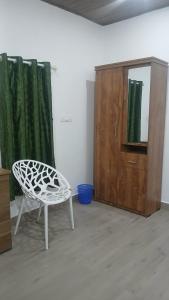 a white chair and a cabinet in a room at Kanthanpara mist stay in Meppādi
