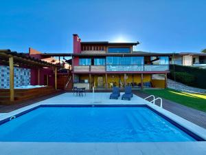 a house with a swimming pool in front of a house at Mirantes Paraibuna - Casa Vermelha in Paraibuna
