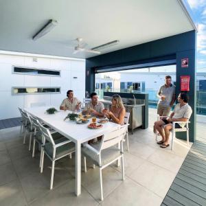 a group of people sitting around a white table in a kitchen at Resort on Cedar in Windang