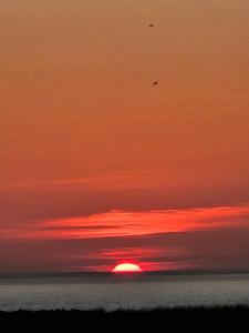 a sunset over the ocean with the sun in the sky at Historic Block Island Suite in New Shoreham