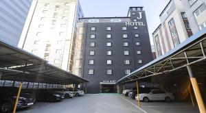 a hotel with cars parked in a parking lot at Osan J Hotel in Osan