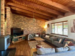 a living room with couches and a brick wall at Hunter Valley 2 x Homes Pets Heated Pool in Whittingham +147 photos
