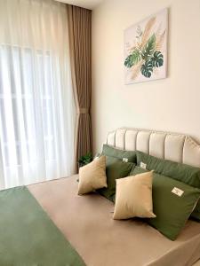 a bedroom with a bed with green and white pillows at MH Home in Long Bình