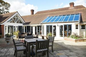 een serre met een tafel en stoelen op een patio bij St Leonards Hotel by Greene King Inns in Saint Leonards