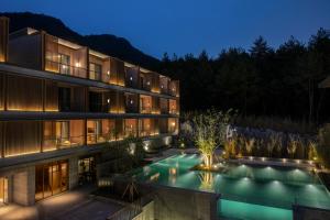 an exterior view of a building with a swimming pool at night at Hotel Indigo Anji by IHG in Anji