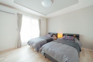 two beds in a white room with a window at Quiet Japanese House near Airport in Kumamoto