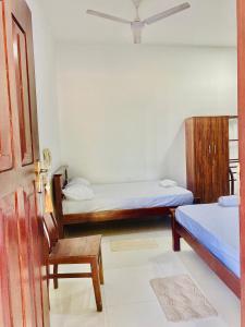 a room with two beds and a chair and a door at Forest Edge Yala Resort in Gotamegama