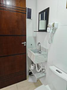 a bathroom with a sink and a mirror and a door at Suites Du'Mauro Terreo in Abraão +12 photos