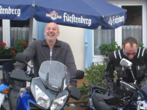two men standing under an umbrella next to a motorcycle at Pension Ochsen, Gästezimmer in Unadingen in Löffingen