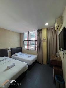 a hotel room with two beds and a flat screen tv at Everstay Inn by Evernent in Miri