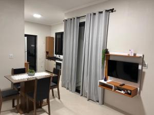 a living room with a television and a dining room table at Casa Mobiliada Conforto e Praticidade in Santa Rosa