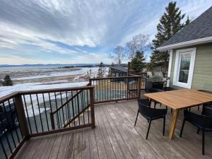 a deck with a wooden table and chairs on a house at L'Anseau-Persil in Rivière-du-Loup