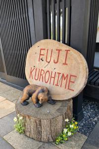 a dog laying on a tree stump with a sign at Fuji-Kurohime- in Shinano +78 photos