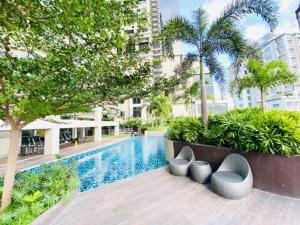 a swimming pool with some chairs next to a building at Studio Getaway in Cebu City Baseline in Cebu City
