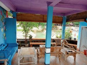 a porch with chairs and tables and a view of the river at Monkey Business Tours & Accommodation in Bukit Lawang
