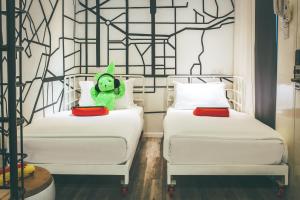 a teddy bear sitting on two beds in a room at Dash Box Hotel Cyberjaya in Cyberjaya