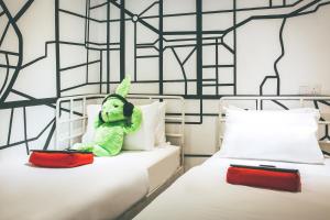 a teddy bear sitting on top of two beds at Dash Box Hotel Cyberjaya in Cyberjaya