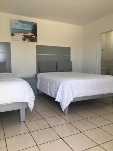 ein Schlafzimmer mit zwei Betten mit weißer Bettwäsche in der Unterkunft Pearl Point Hotel in Puerto Peñasco