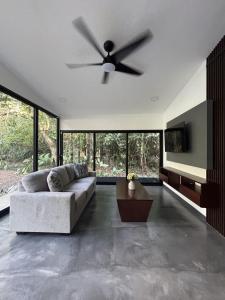 a living room with a couch and a ceiling fan at Luxury Riverfront House 3BR BBQ Jungle views & walk to river in Parrita