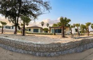 a stone retaining wall in front of a house at Wind Haus Beachfront Villa in Ban Hat Chao Samran