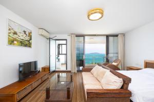 a living room with a couch and a tv at Yumian Cloud Seaview Hotel in Sanya