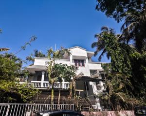 a white house with palm trees in front of it at Redwing Peaceful Studio in Navi Mumbai