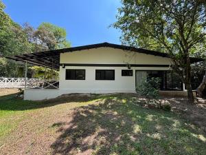 a white house with a tree in front of it at Luxury Riverfront House 3BR BBQ Jungle views & walk to river in Parrita