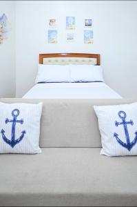 a bed with two blue anchor pillows on it at Condotel in SM Trece Martires in Trece Martires +9 photos