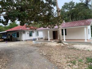 a white building with a tree in front of it at Homestay kampung dusun in Balik Pulau