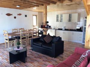 a living room with a black couch and a kitchen at Cabañas Vista Parapentes in Maitencillo