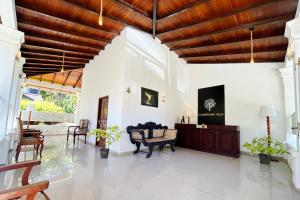a living room with white walls and a wooden ceiling at Ilamperuma Bungalow in Weligama