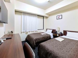 a hotel room with two beds and a desk at Dai-ni Sunny Stone Hotel in Osaka +8 photos