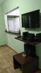 Habitación con TV, mesa y espejo. en Apartamento Pitangueiras - Guaruja, en Guarujá