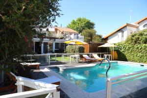 a swimming pool with two chairs and an umbrella at Bernie's Bed & Breakfast , A 3 KILOMETROS DEL AEROP EZEIZA, VAN ,IN-OUT, FREE EZEIZA AIRPORT in Ezeiza