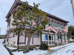a house with a tree in front of it at 国登録有形文化財の宿 Hotel 旧若林邸 in Sado