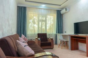 a living room with a couch and a table and a television at Asson Hotel Termez in Termiz