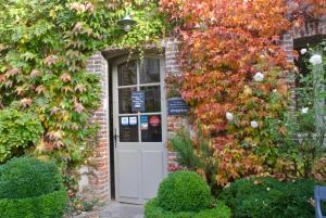 a brick house with a white door and ivy at La Cour Sainte Catherine demeure de charme in Honfleur
