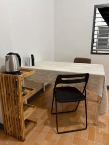 a table with a black chair next to a kitchen at Mama's Tree Homey Studio in Ban Klaeng Lang