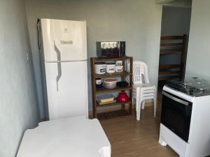 a kitchen with a white refrigerator and a table at Apê Bianck's in Ilha Comprida