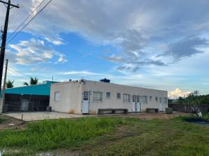 an old white building in a field with a cloudy sky at Apê Bianck's in Ilha Comprida